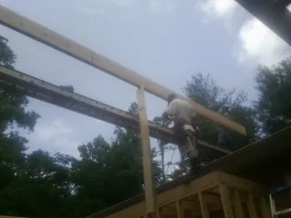 Carpenter setting a ridge beam over a new addition frame — Ice Dam Removal by Roofing Brothers in Bronx