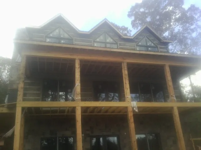 Dormers and porch framing on a large log home under construction — Roof Coating work by our crew in Bronx