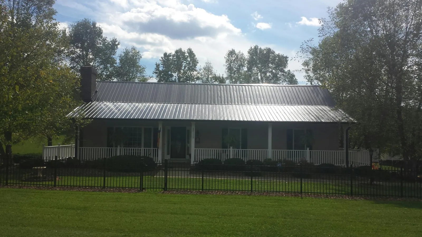 Gray metal roof on a brick ranch with a full width front porch — Gutter Guard Installation work by our crew in Bronx