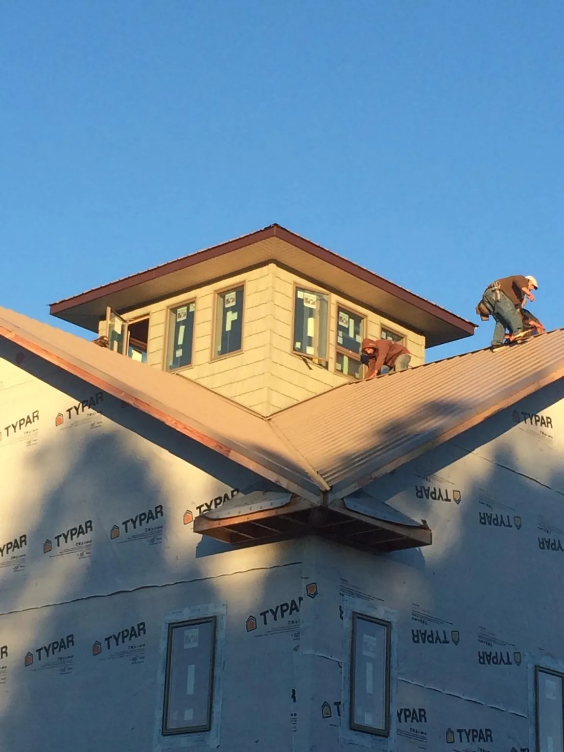 Roofers working around a rooftop cupola on a new metal roof at sunset — Roof Waterproofing in Bronx by Roofing Brothers